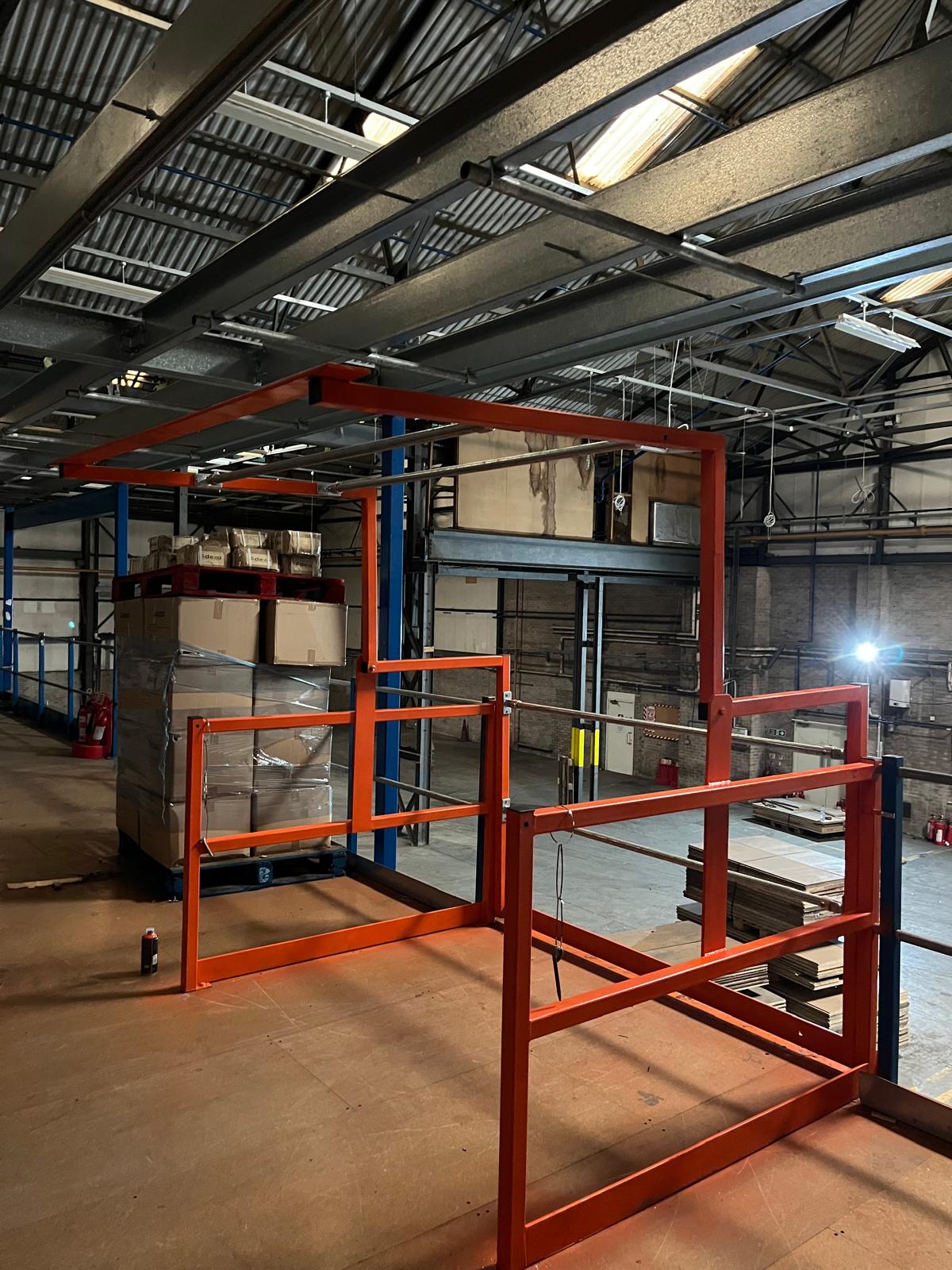 An orange painted safety pallet gate fitted to the edge of a mezzanine floor